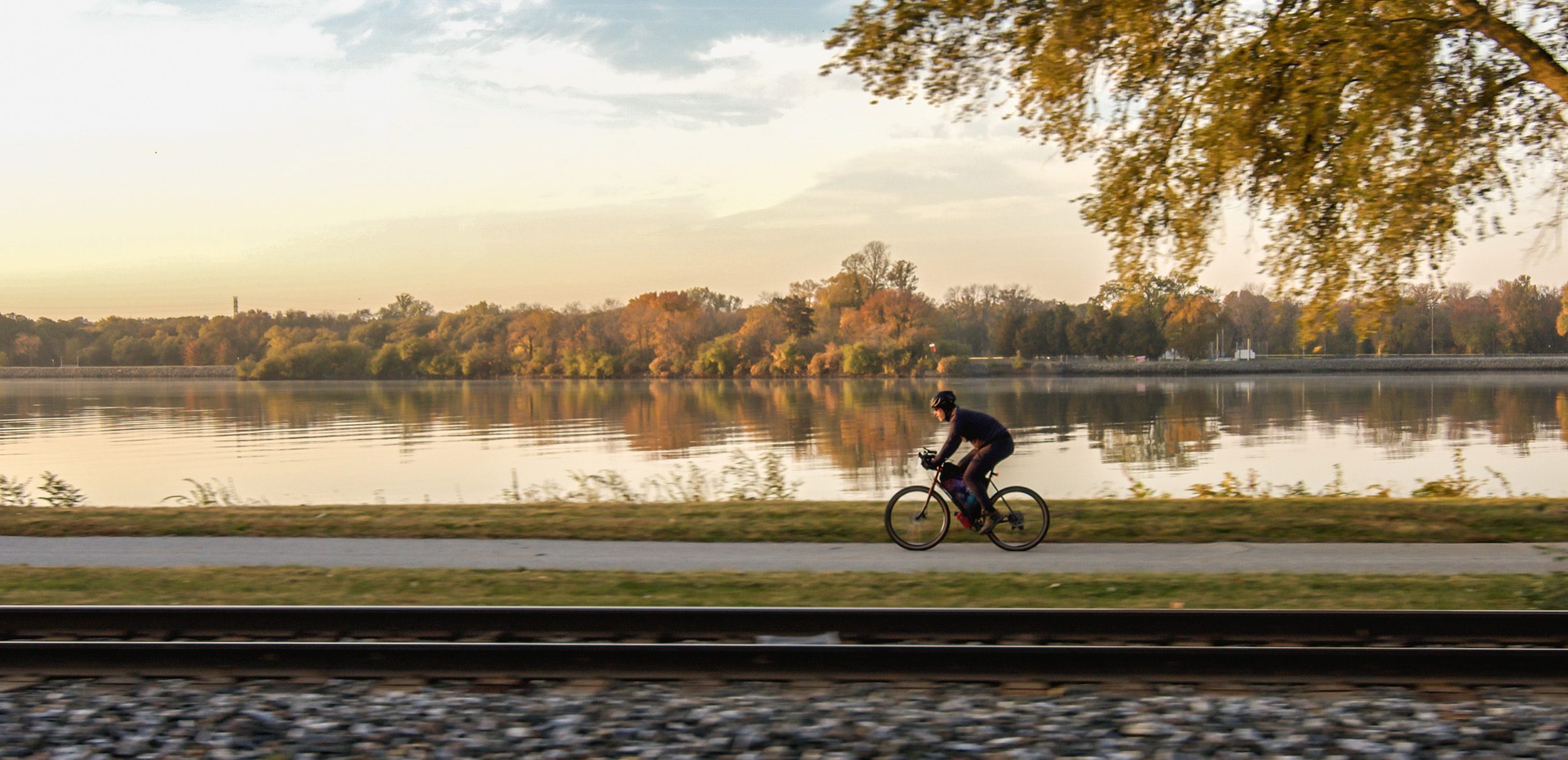 man biking next to river during sunset in the Quad Cities