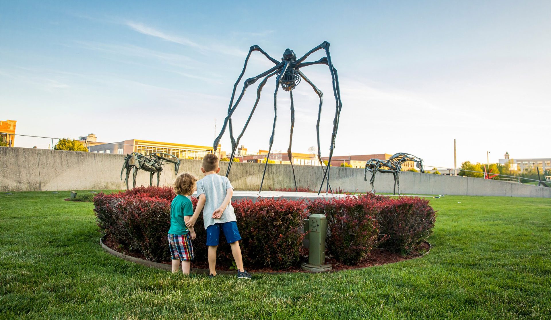 kids viewing a sculpture of a large insect at the poppajohn sculpture park in des moines iowa