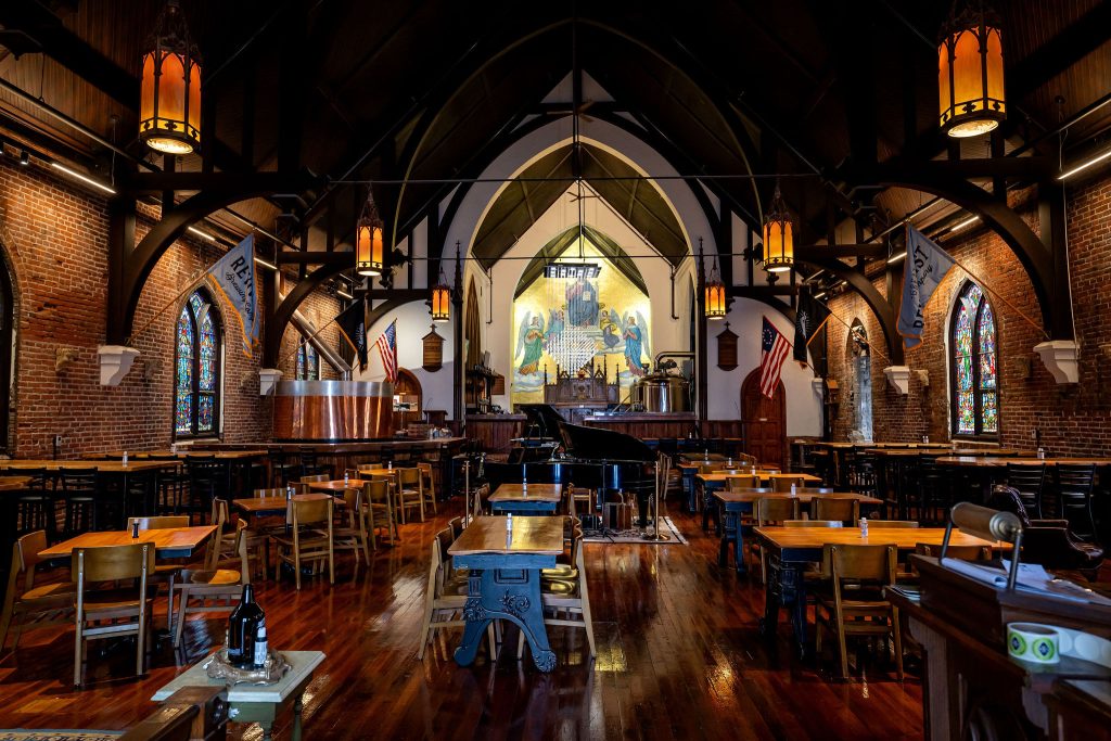 A historic church has tables and chairs to serve patrons as a brewery