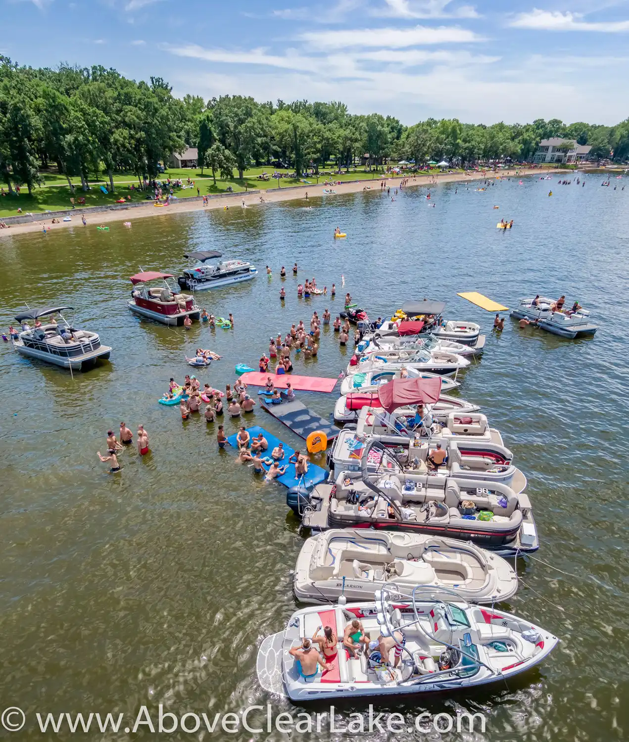 People gather on anchored boats and floating rafts in Clear Lake