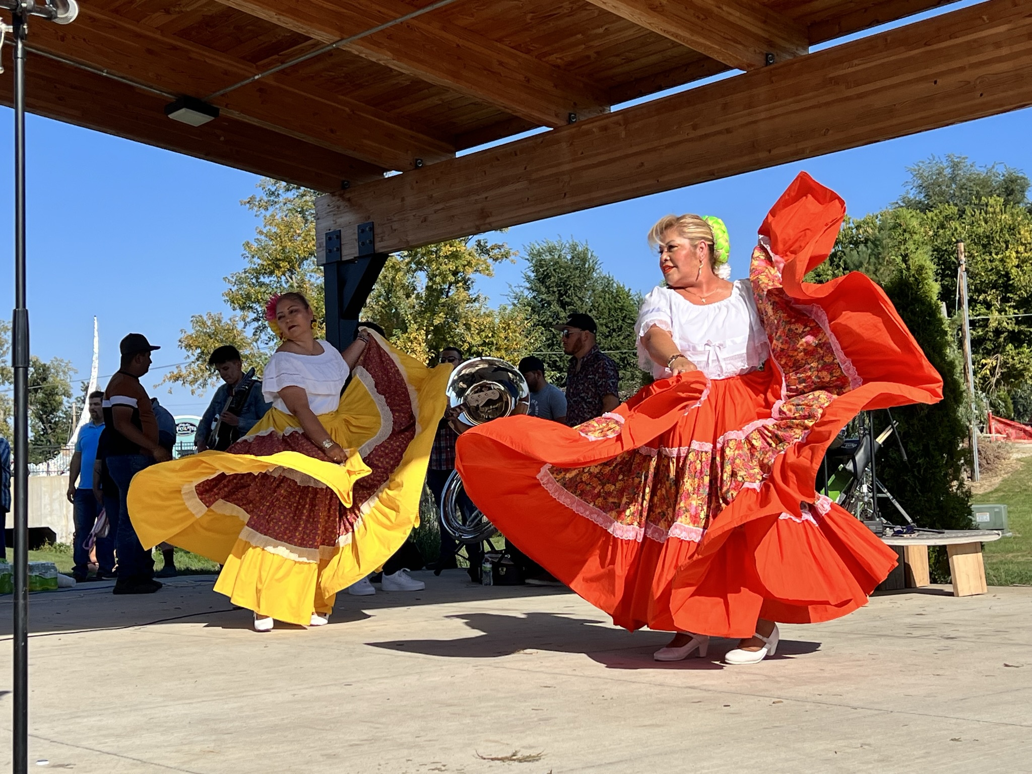 Women dancing in bright yellow and red cultural clothing at a festival in Marshalltown, Iowa