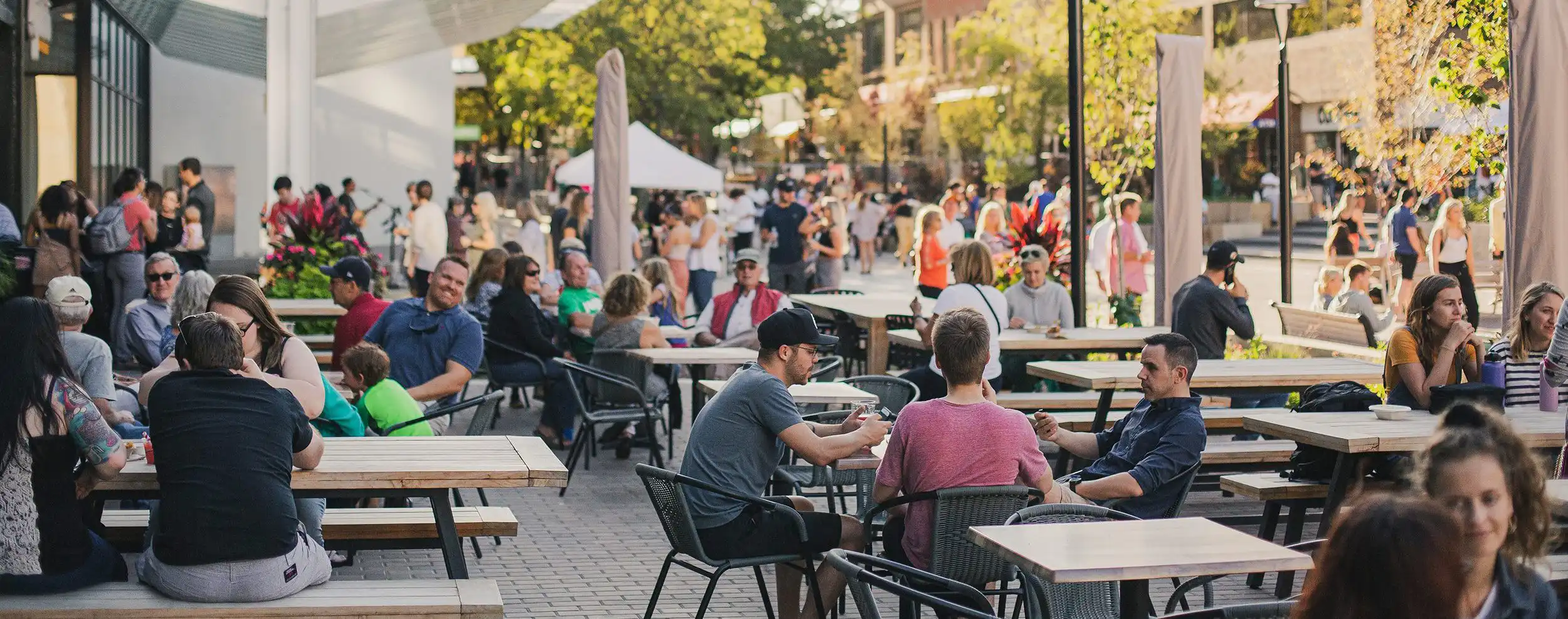 crowd of people sitting at tables and walking around at Iowa City pedestrian mall