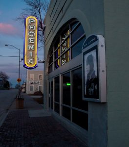 Exterior view of the Phoenix Theatre at night with the neon sign lit.