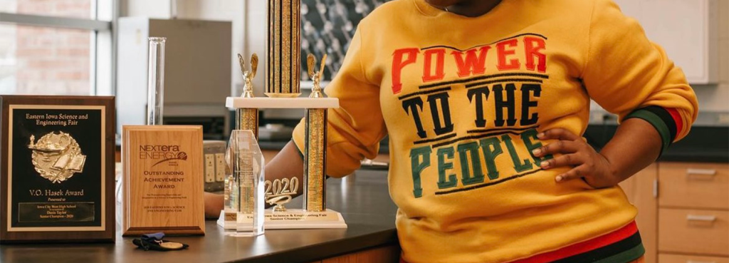 Close up view of Dasia's awards with her Power to the People shirt in the background.
