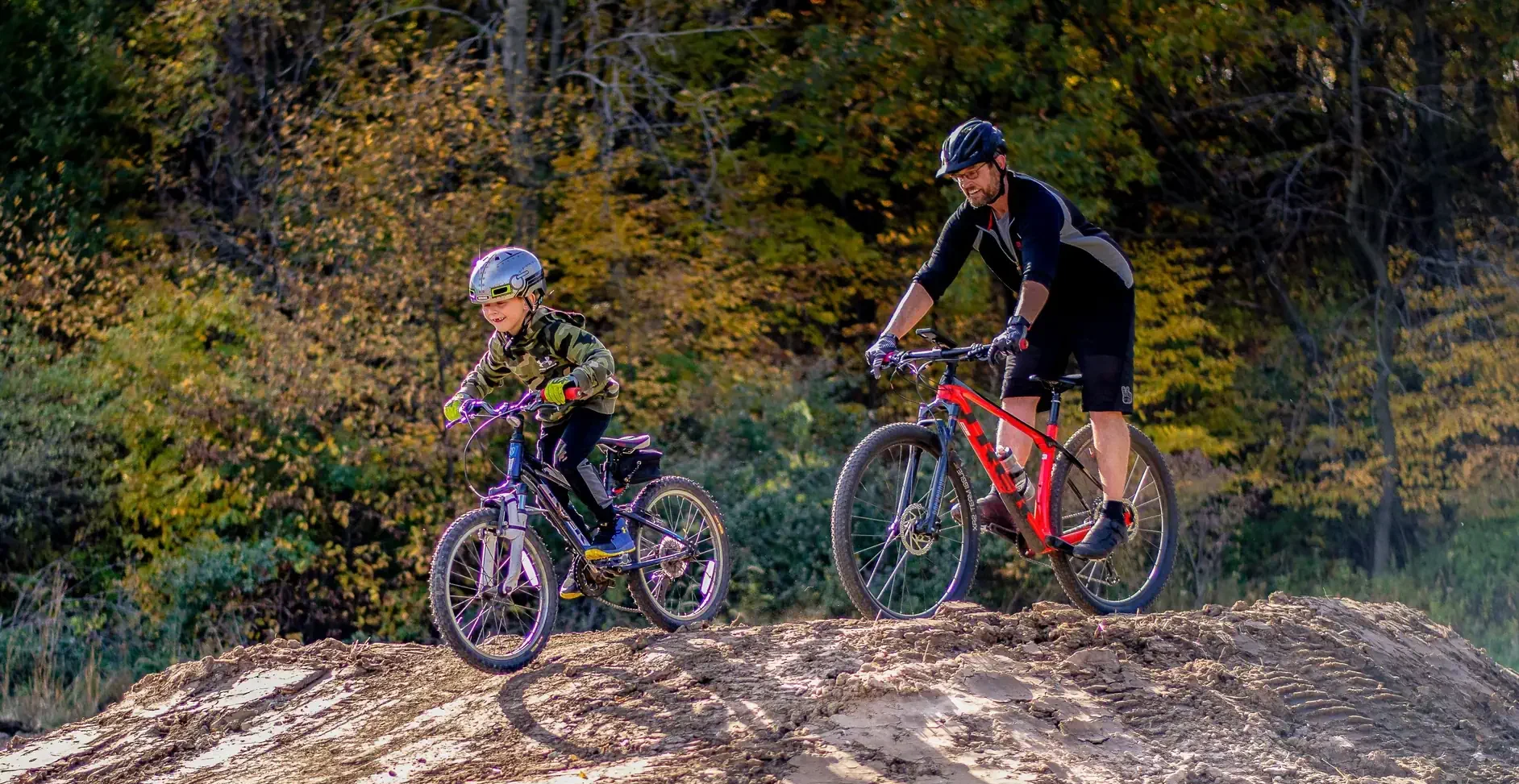 Father and sone riding bikes offroad in a park setting.