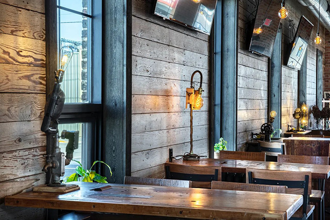 Tables lining the interior wall of Textile Brewery to showcase the wood paneling and rustic decor.