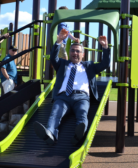 Marion Mayor Nick AbouAssaly sliding down a slide at a local playground.