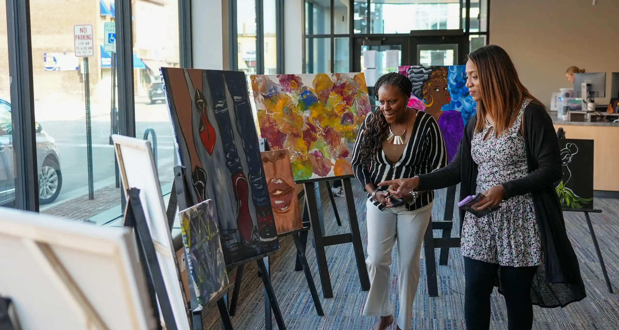 two women viewing artwork on easels