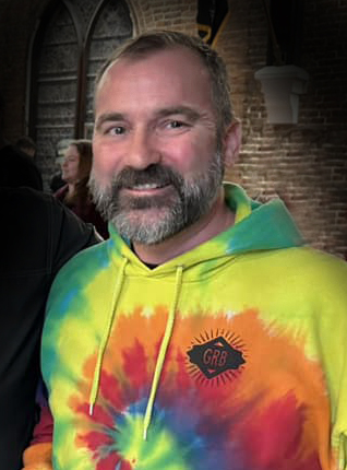 A smiling Richard Schwab in a tie dyed Great Revivalist Brewery sweatshirt.
