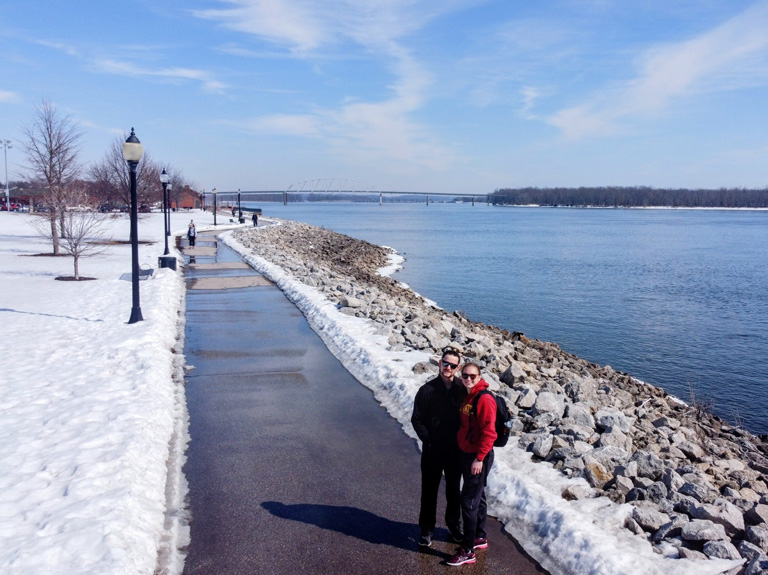 Maggie and Tom Gouger standing on a walking path next to a river in the winter.