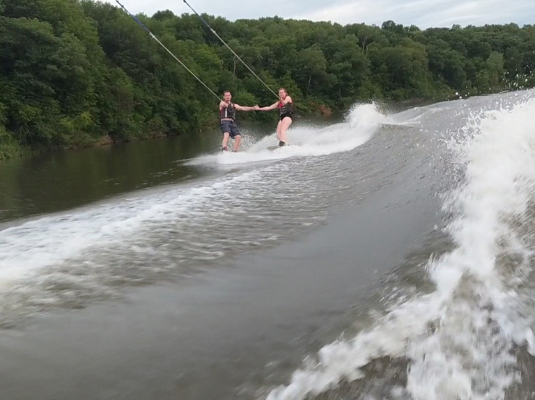 Two people tandem wake boarding on the river. 