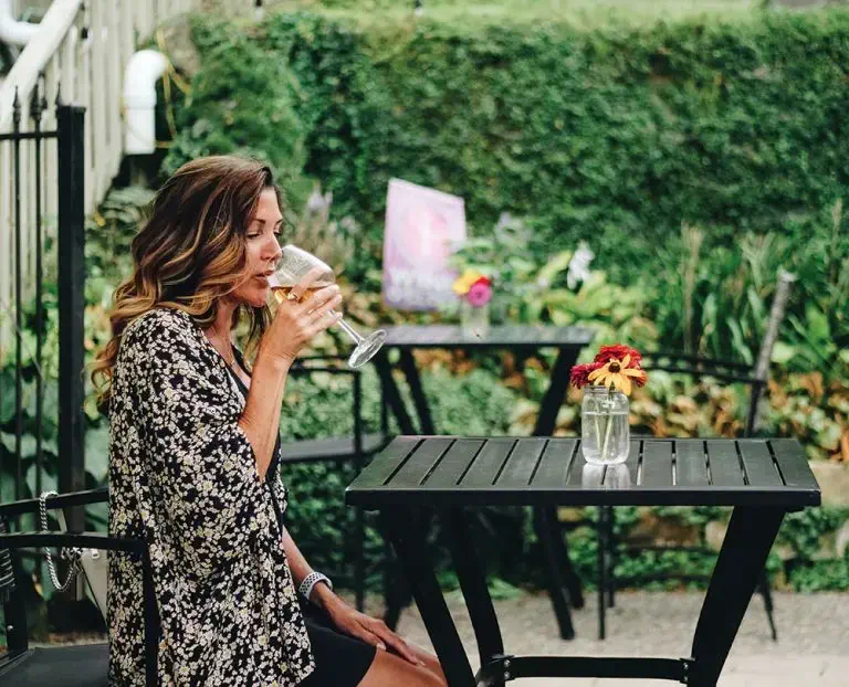A woman sipping a glass of white wine on the patio of a local Iowa vineyard.