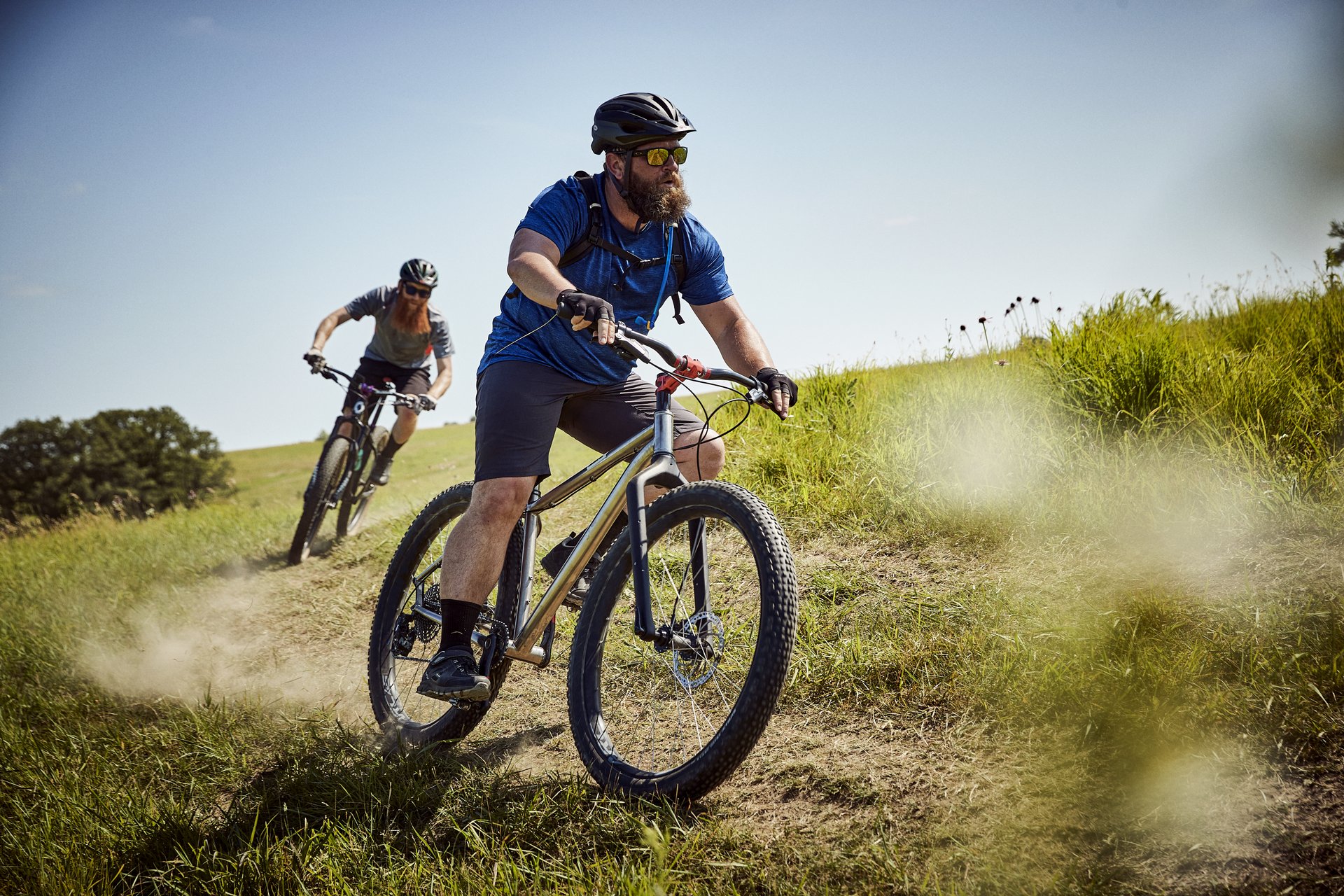 two men riding bikes on unpaved trail