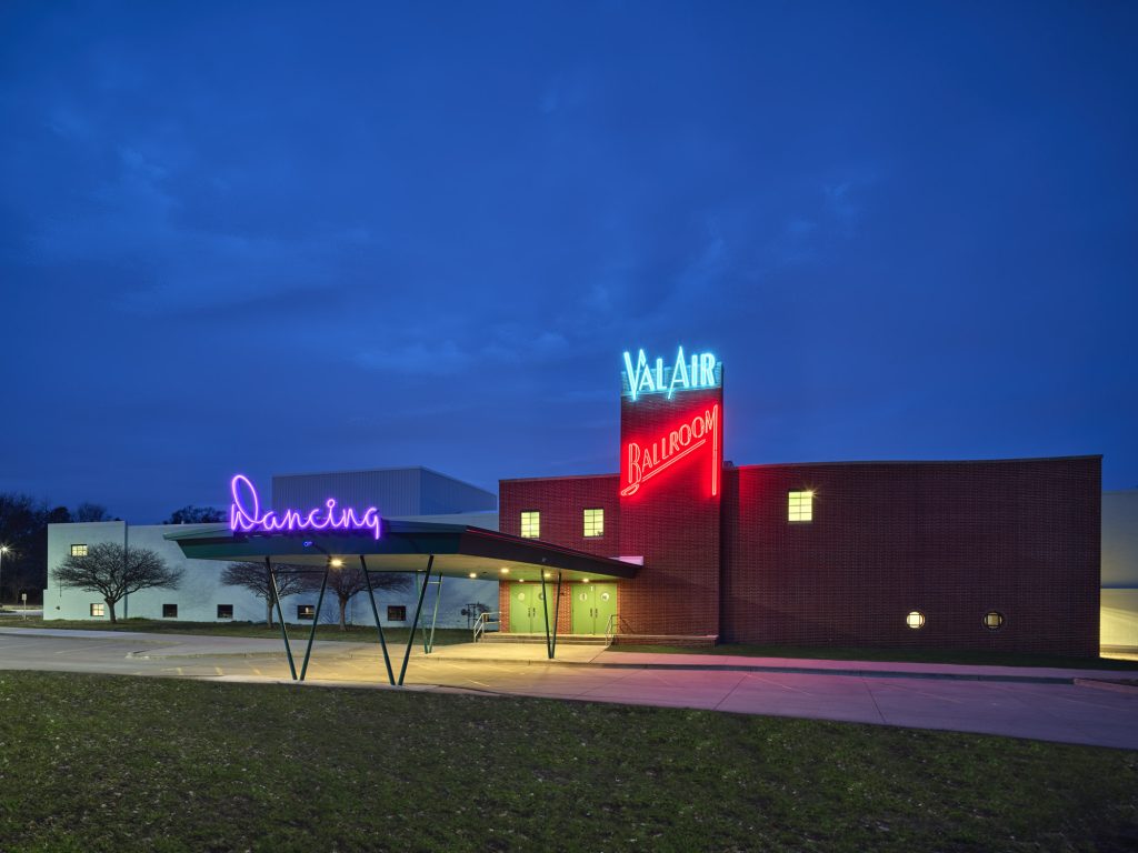 Exterior view of Val Air Ballroom at night with neon signage