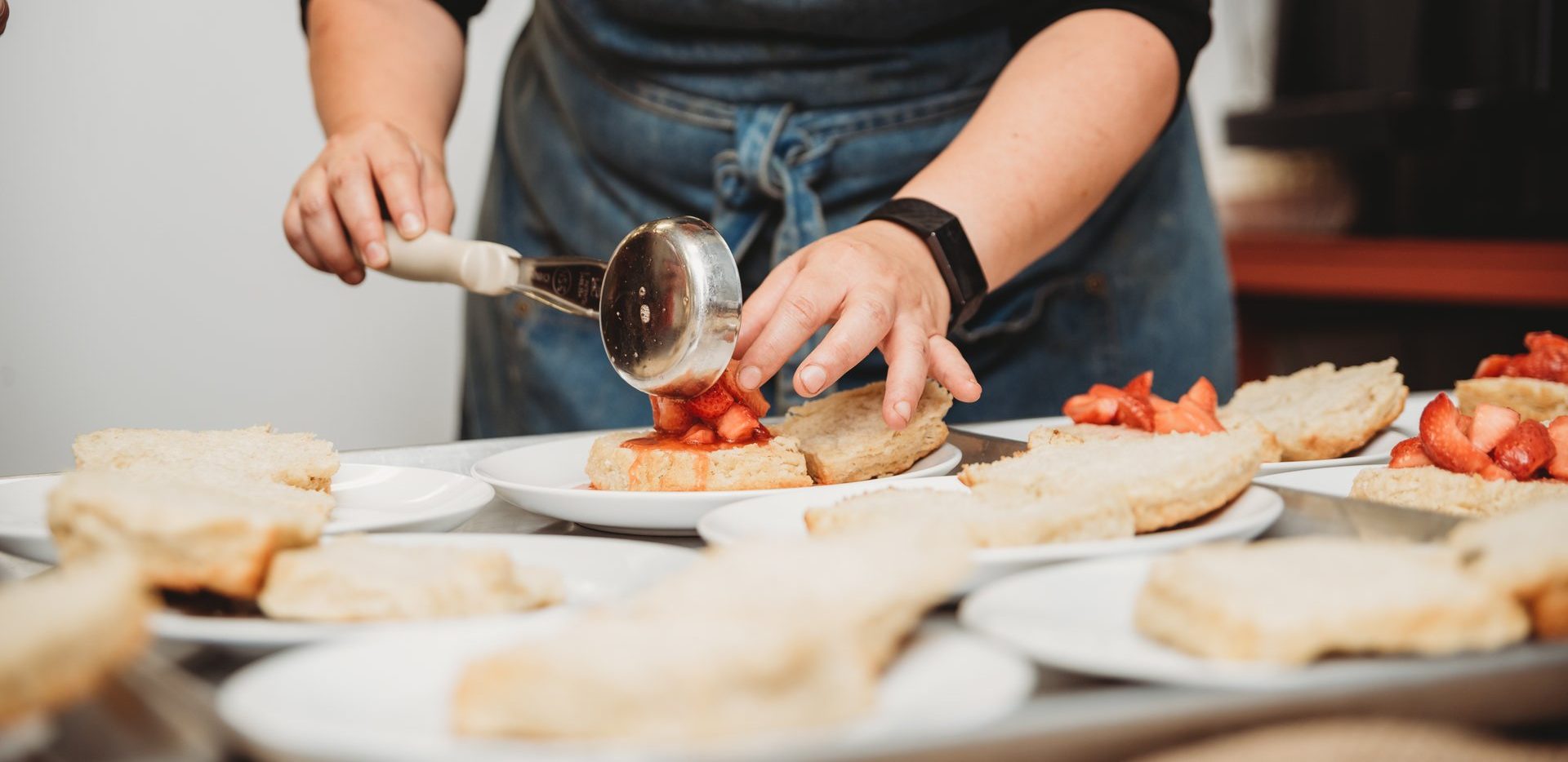 close-up shot of someone pouring strawberry filling on shortcakes