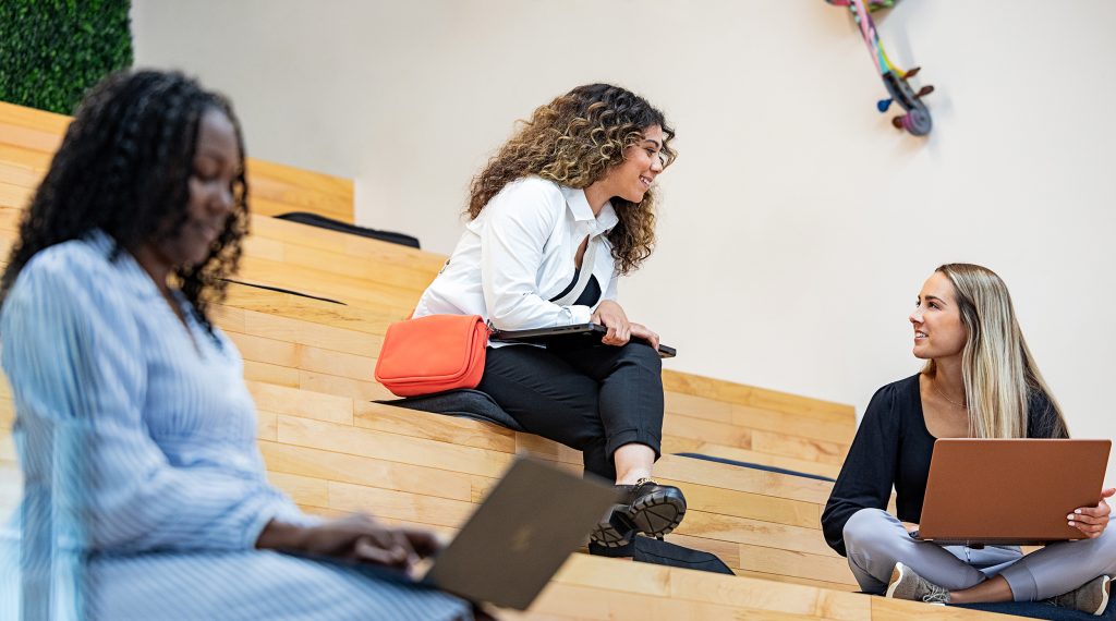 Three women working on laptops in a coworking space