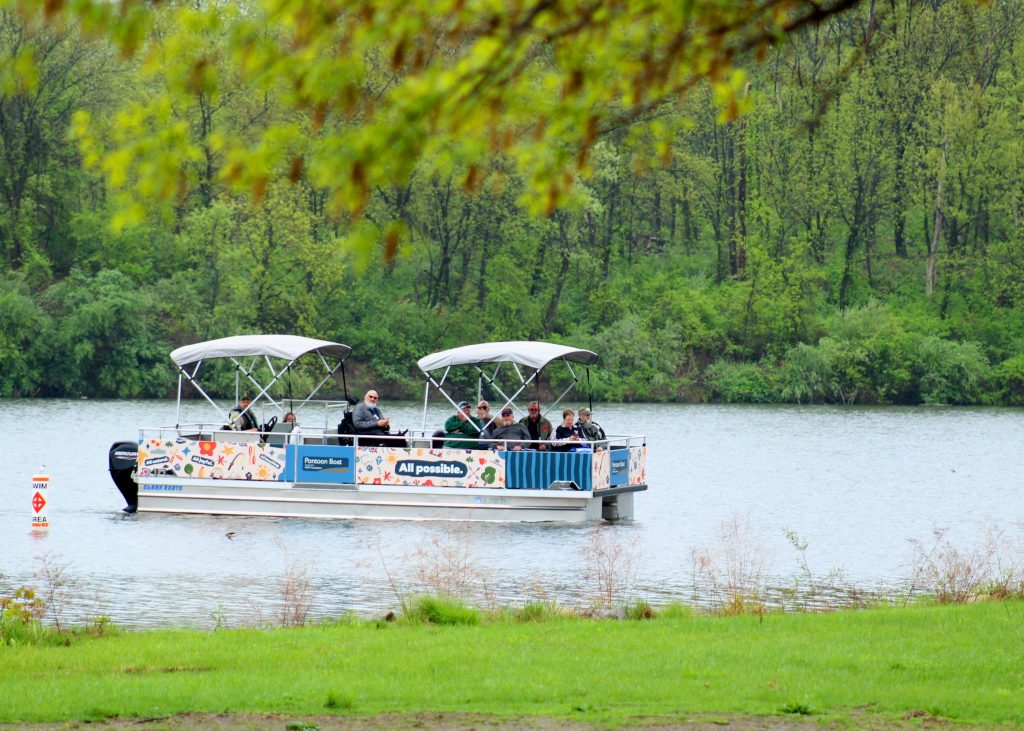 A group of veterans, some in wheelchairs, ride aboard a pontoon boat.