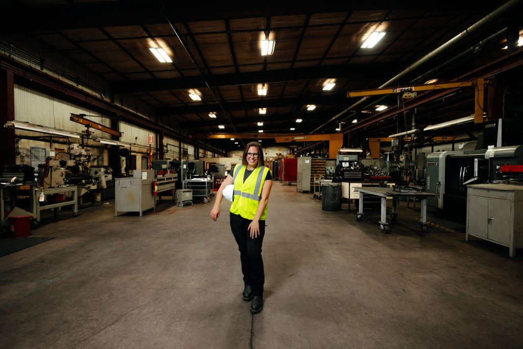 Woman wearing a safety vest standing in factory space.