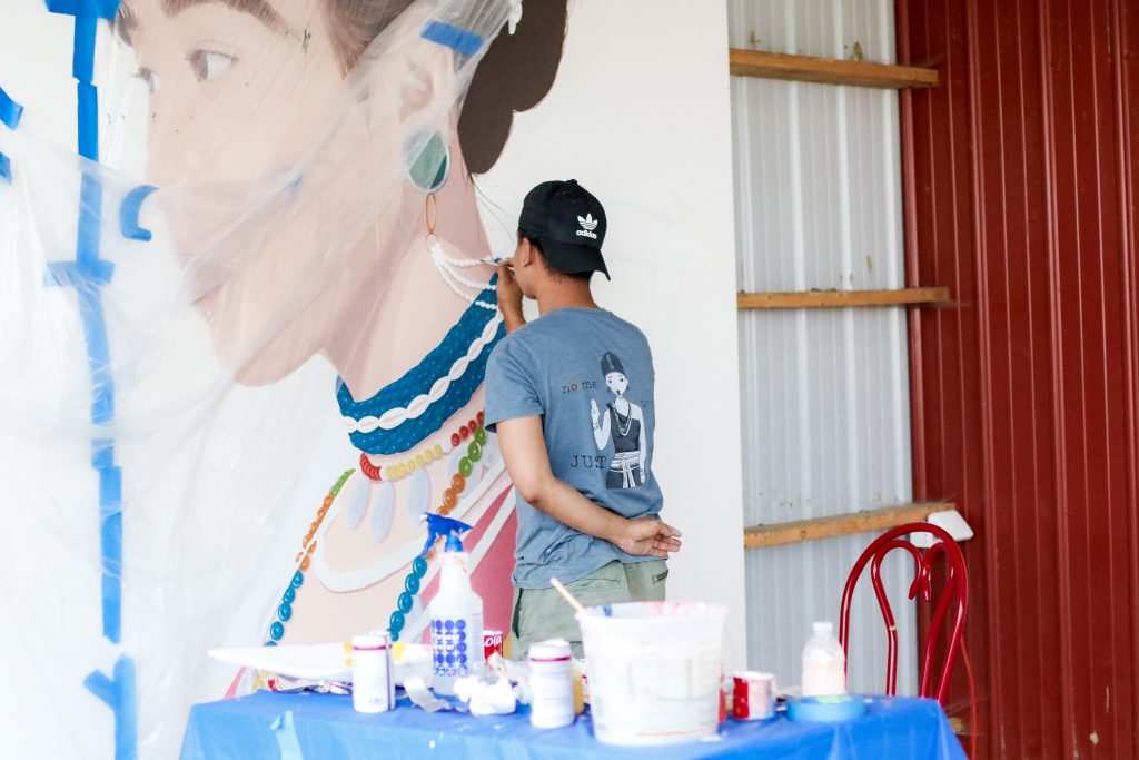 man paints mural