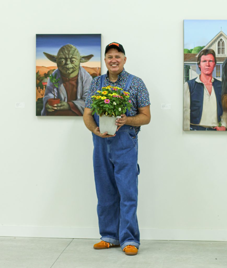 man holds a potted plant inside art gallery