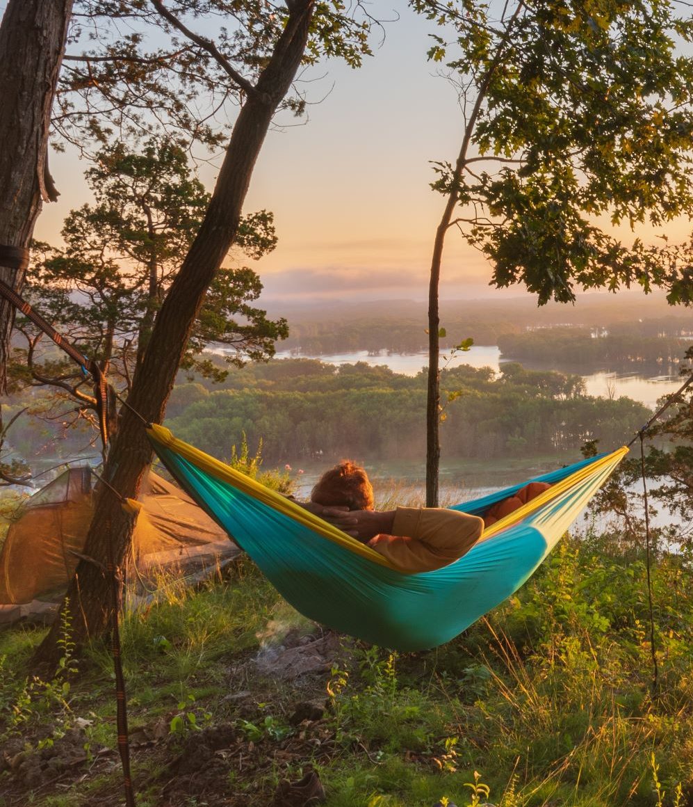 person in hammock looking over a river