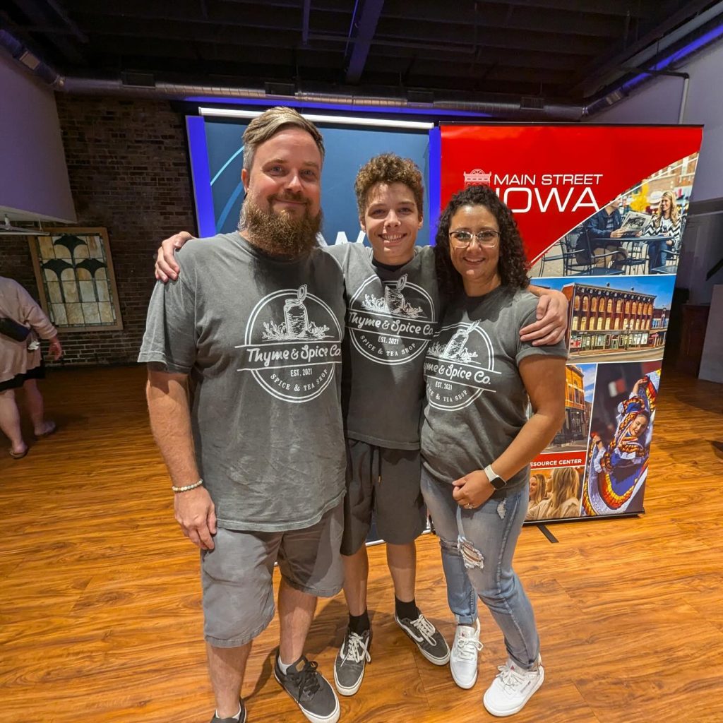 three people standing in front of banner labeled Main Street Iowa