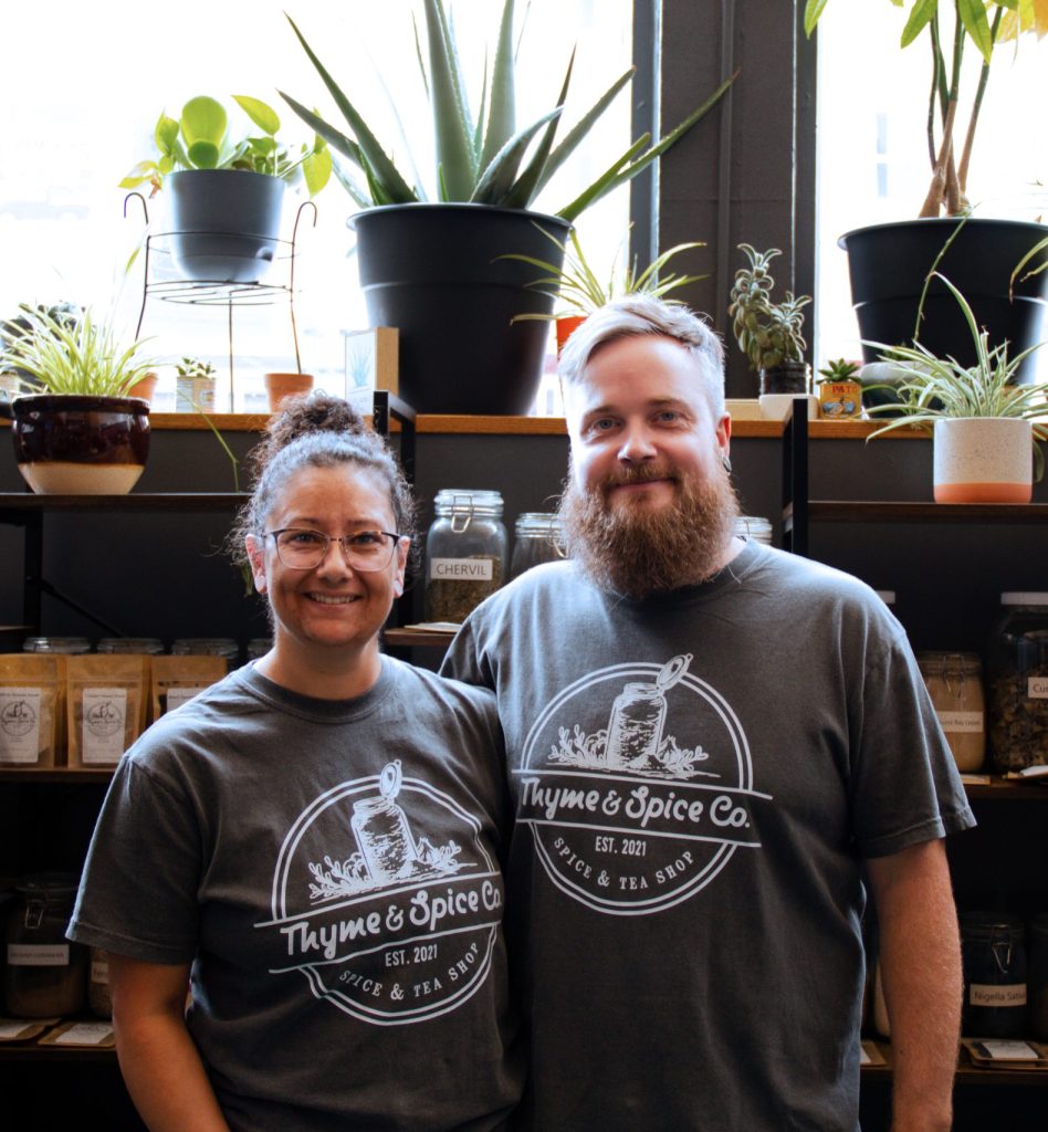 couple standing in front of store shelves full of spices and plants