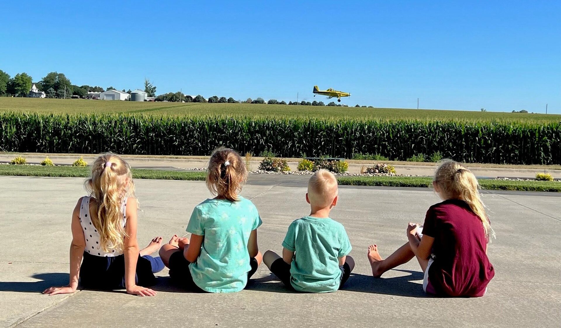 kids sitting by a corn field