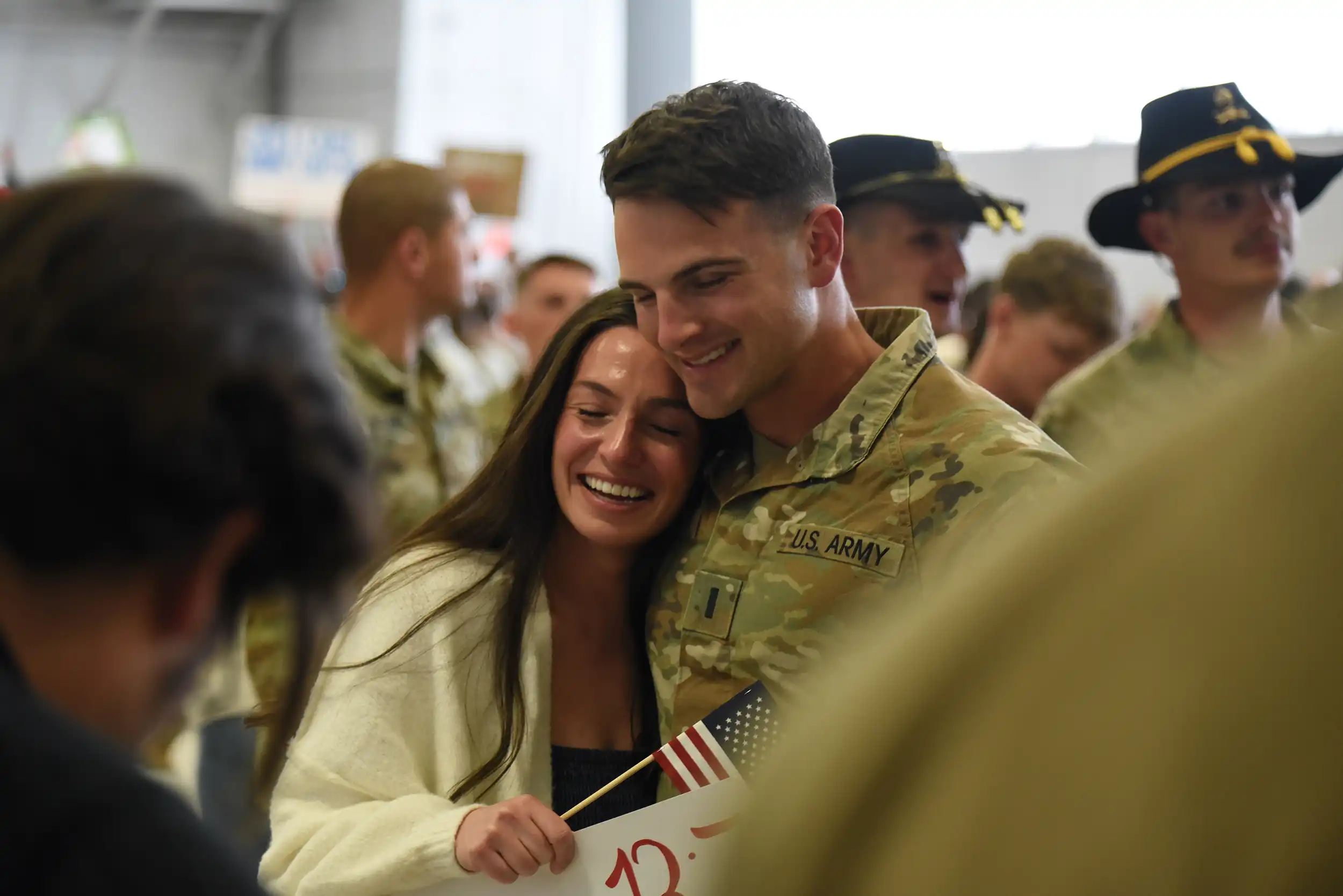 A man in military fatigues hugs his wife
